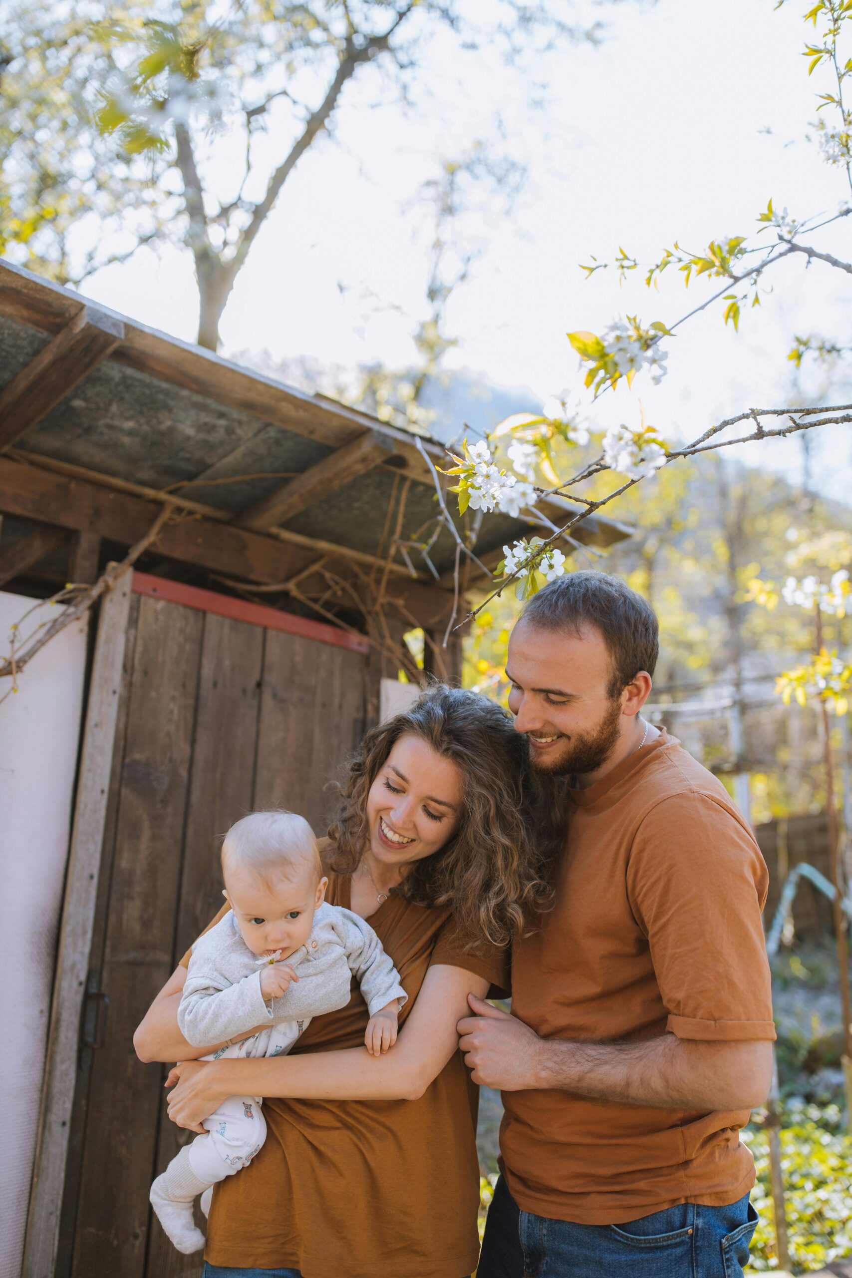 Smiling family with baby enjoying a sunny day outdoors, capturing a moment of affection and joy.